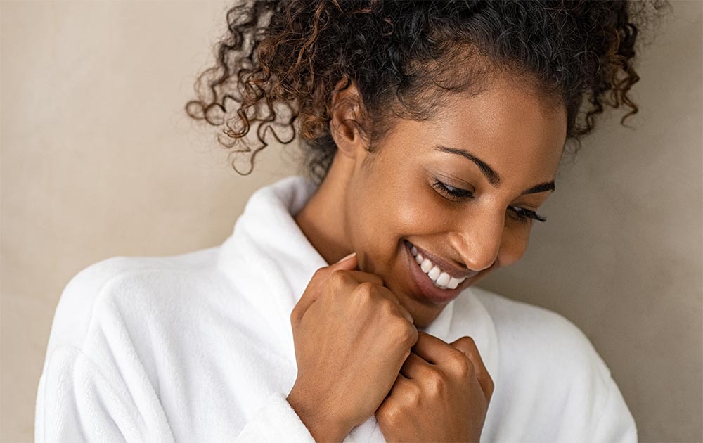 Lady wearing a fluffy white robe treated with textile chemical solutions to enhance fabric softness and water absorption. 
