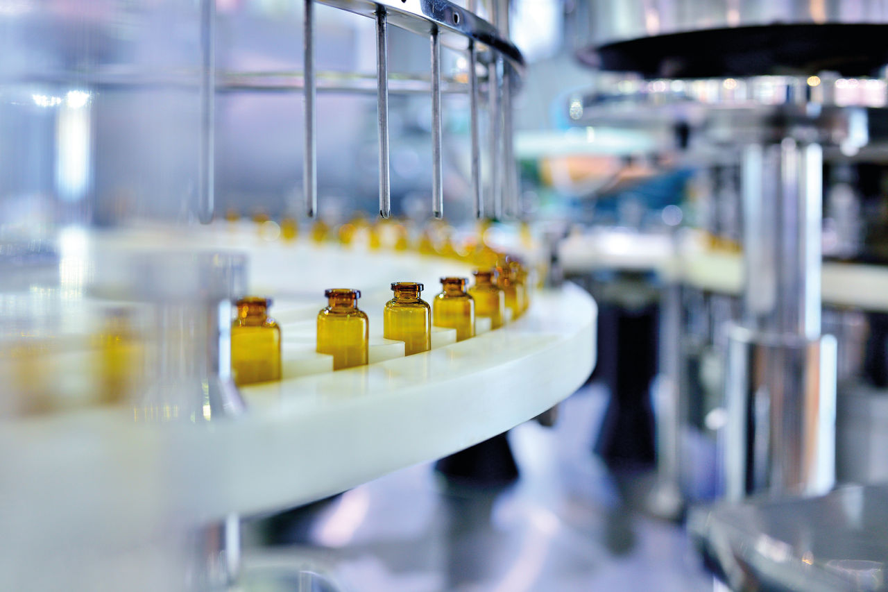 Close-up of brown glass bottle filling at production line