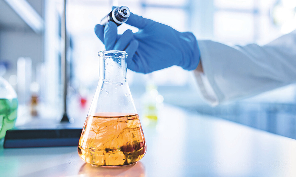 Laboratory experiment with amber solution in flask demonstrating Niax and GeoCell catalysts for efficient, low-emission polyurethane foam manufacturing.