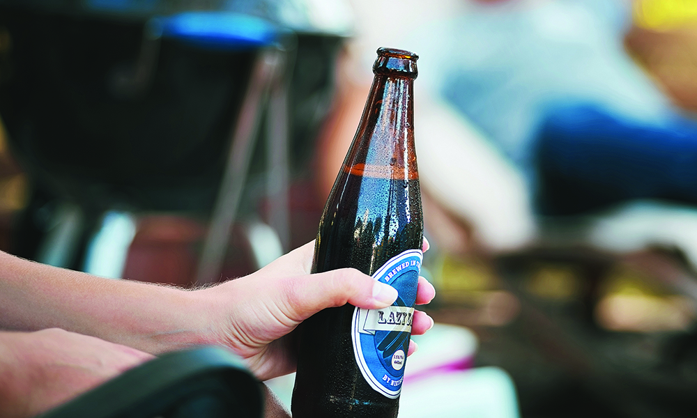 Cropped shot of a woman holding a bottle of beer at a get together