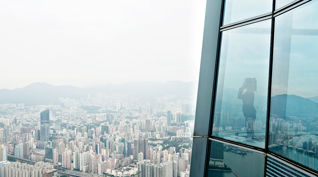 Businesswoman standing in a skyscraper building viewing over the city.